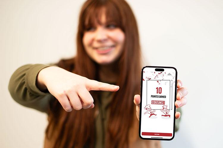 Woman pointing at a mobile phone with a Cousins Subs app screen